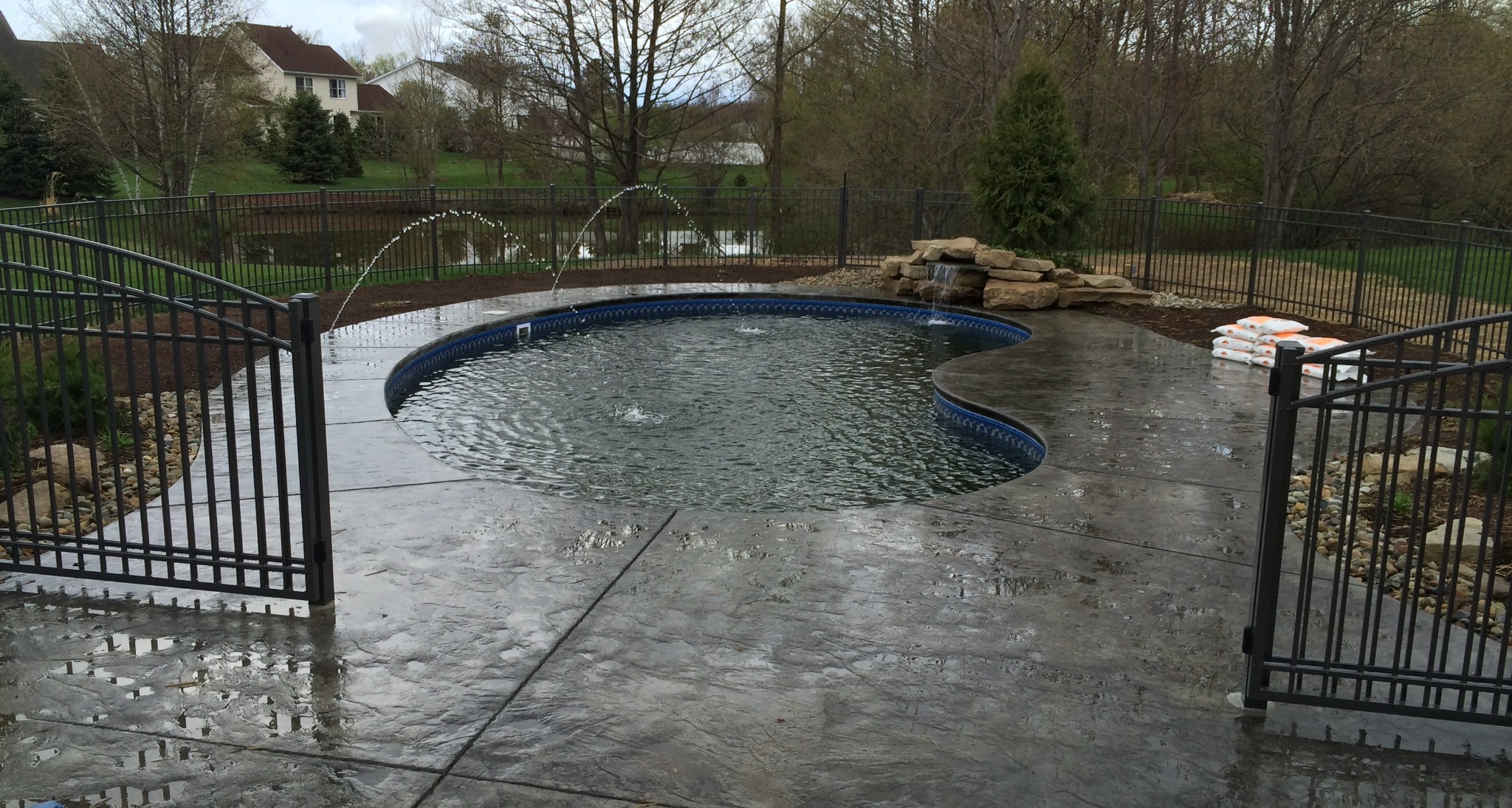 Freeform backyard pool with water features and decorative concrete surround